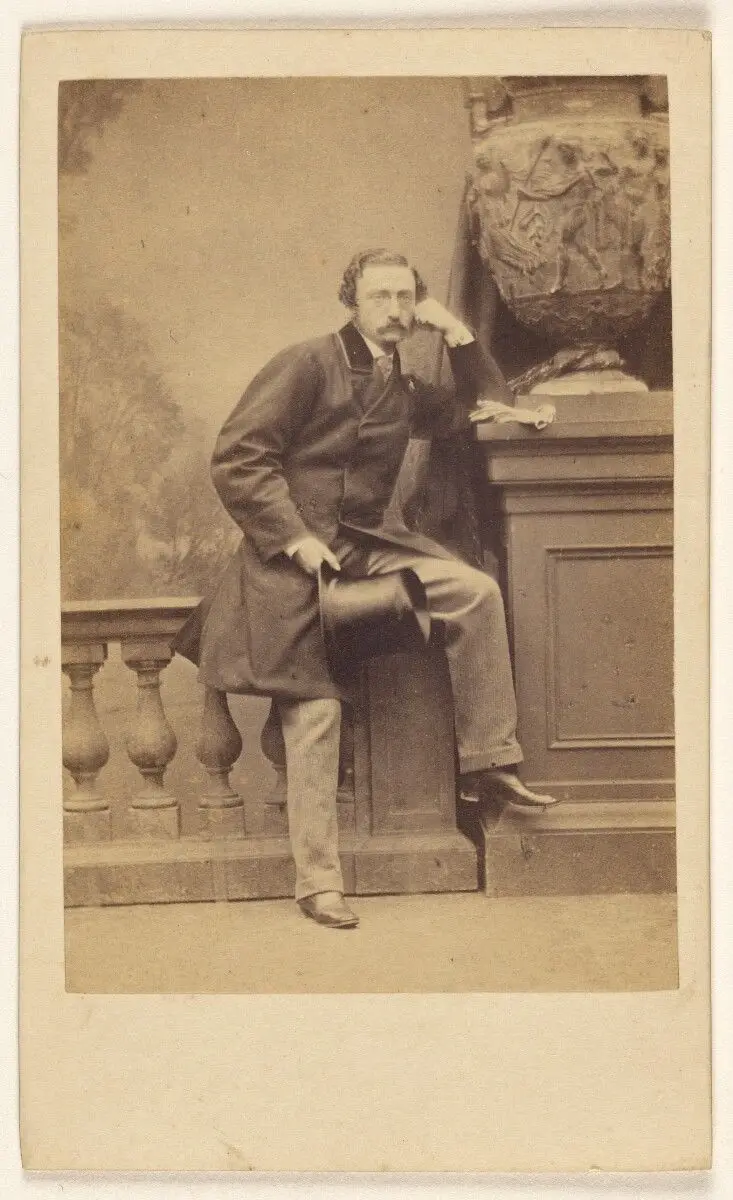 [Man with moustache, holding a top hat, standing, posed on railing in studio] by Antoine Claudet