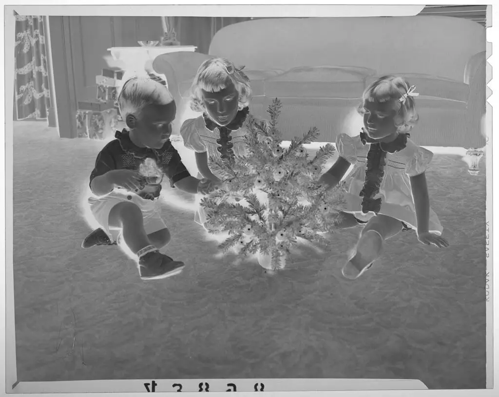 Untitled (three young children sitting on living room floor looking at miniature Christmas tree) by Martin Schweig
