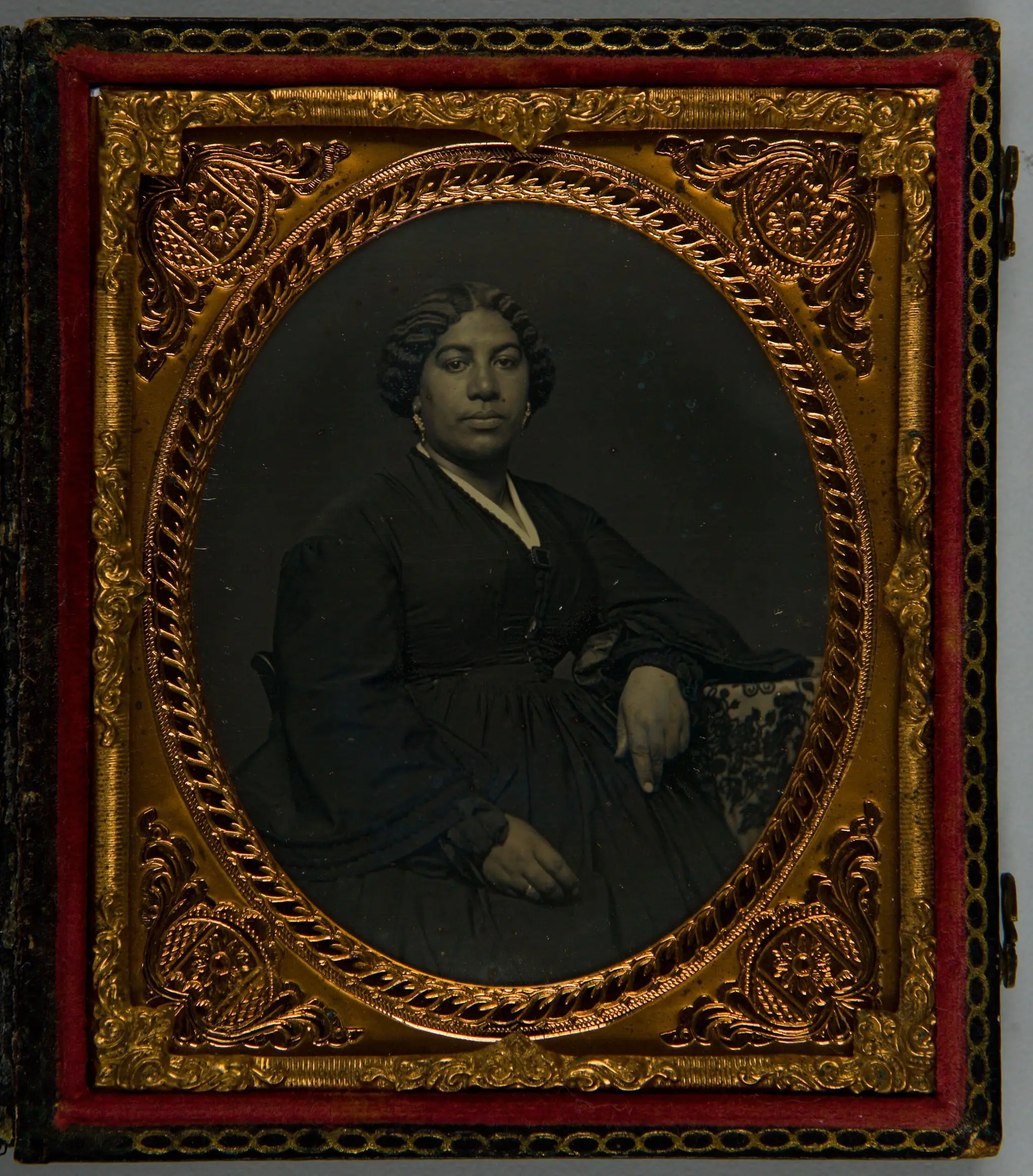 Untitled (half length portrait of African American woman, seated and leaning against tapestry-covered table) by Unidentified Artist