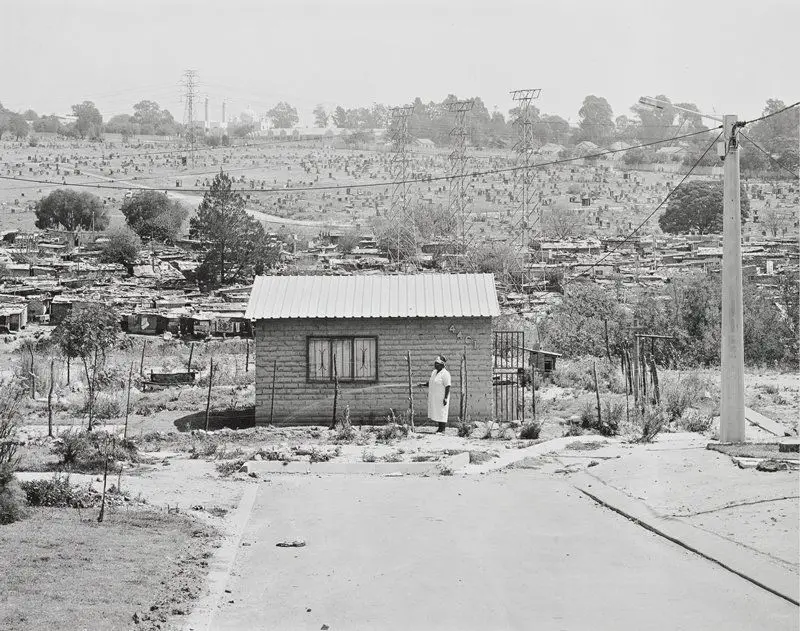 Miriam Mazibuko waters the garden of her RDP house for which she waited eight years. It consists of one room. Her four children live with her in-laws. Extension 8, Far East Alexandra Township by David Goldblatt