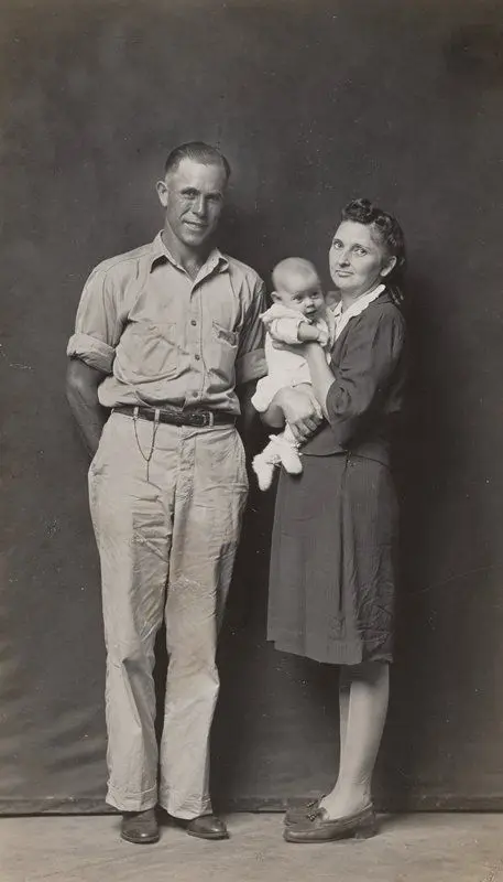 Standing father and mother holding baby by Mike Disfarmer