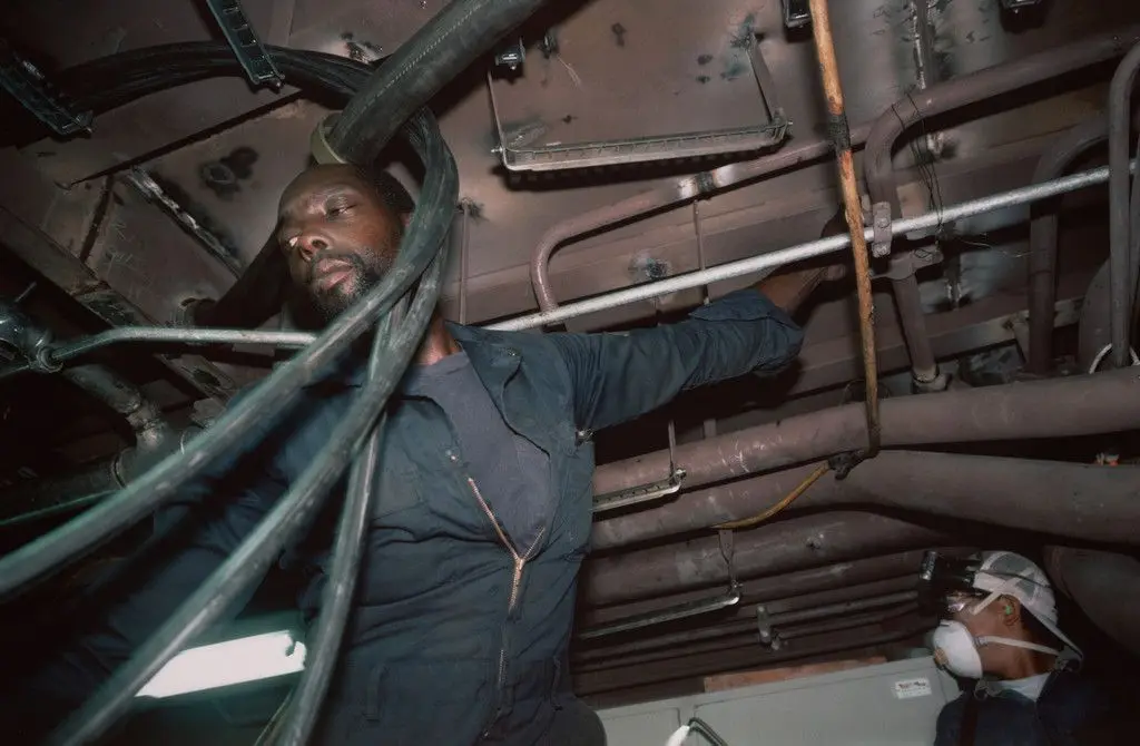 Pipe fitters finishing the engine room of a tuna-fishing boat. Campbell Shipyard. San Diego harbor from the series Fish Story by Allan Sekula