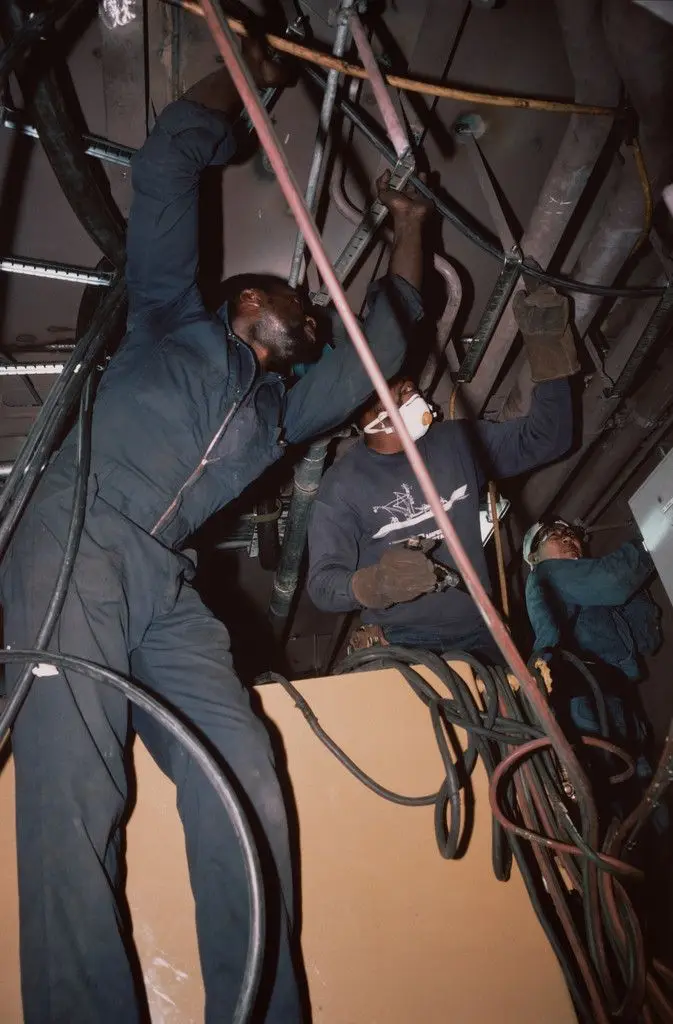 Pipe fitters finishing the engine room of a tuna-fishing boat. Campbell Shipyard. San Diego harbor from the series Fish Story by Allan Sekula