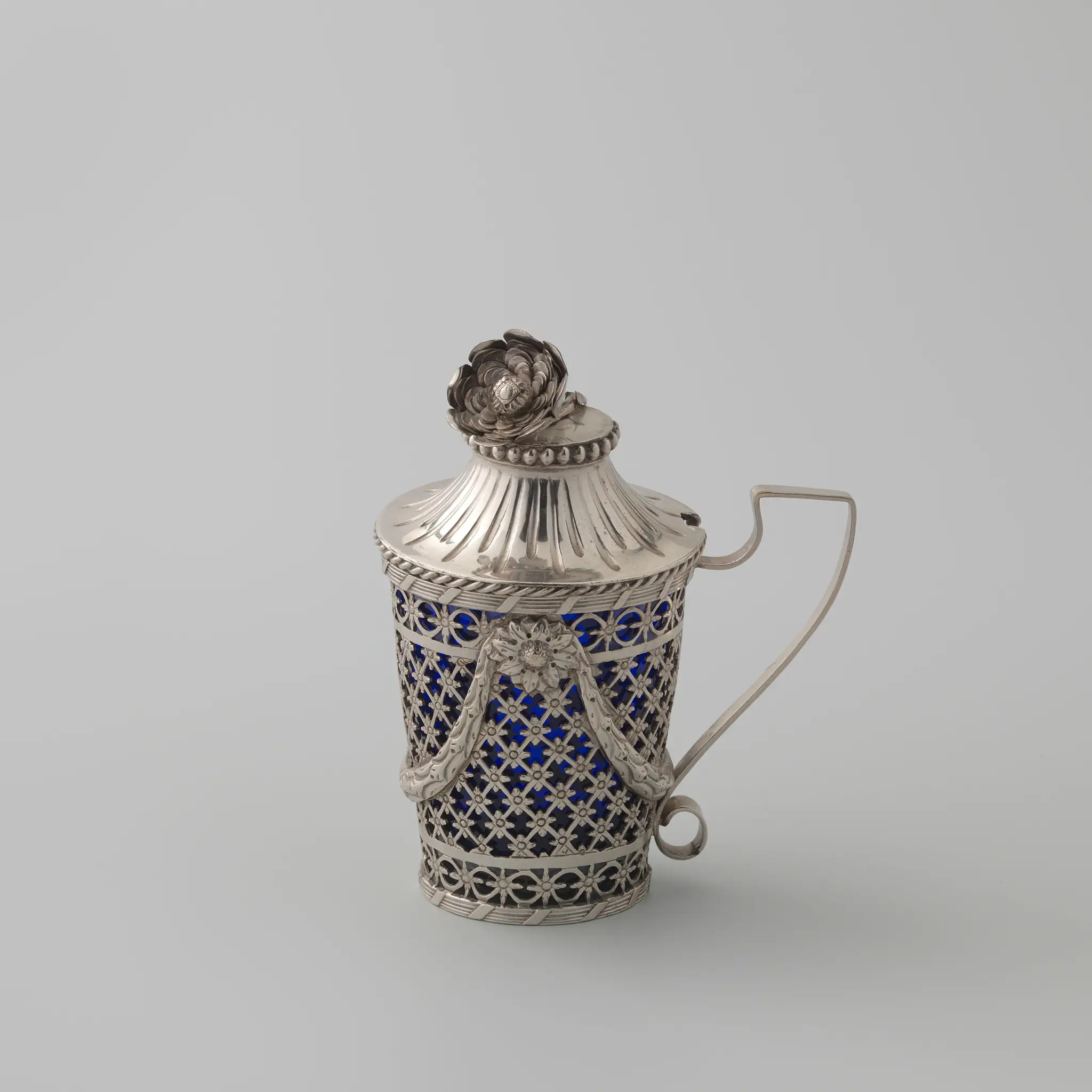 Mosterdpot van zilver, rond en naar boven uitlopend met gezaagd rasterwerk met bloemrozetten en geappliqueerde guirlandes; binnenbak van blauw glas by Johannes Andringa
