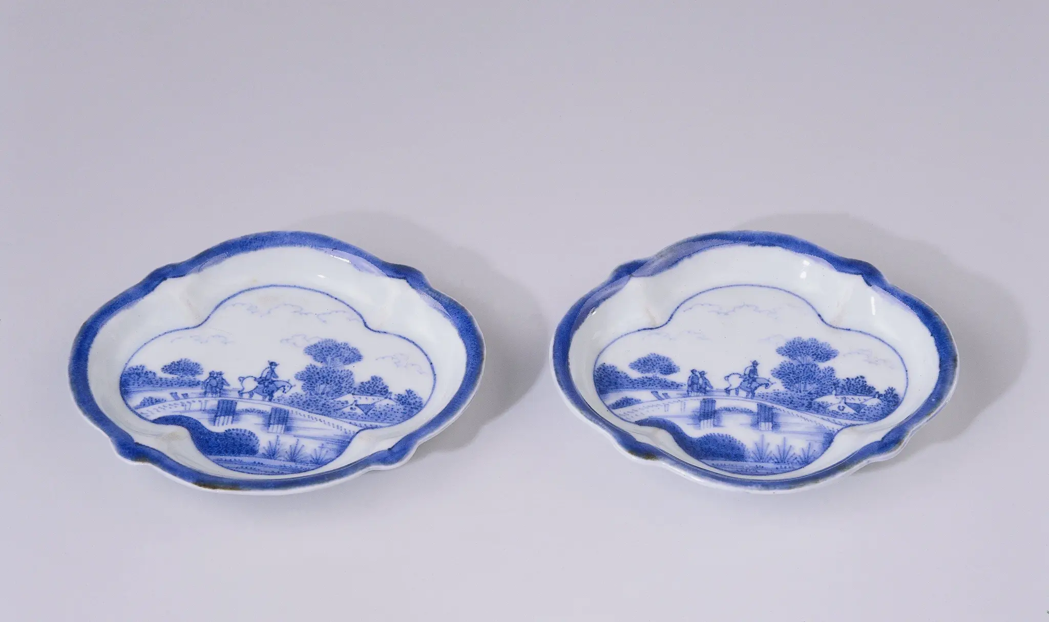 Saucer with figures on a bridge in a water landscape with trees and houses by anonymous