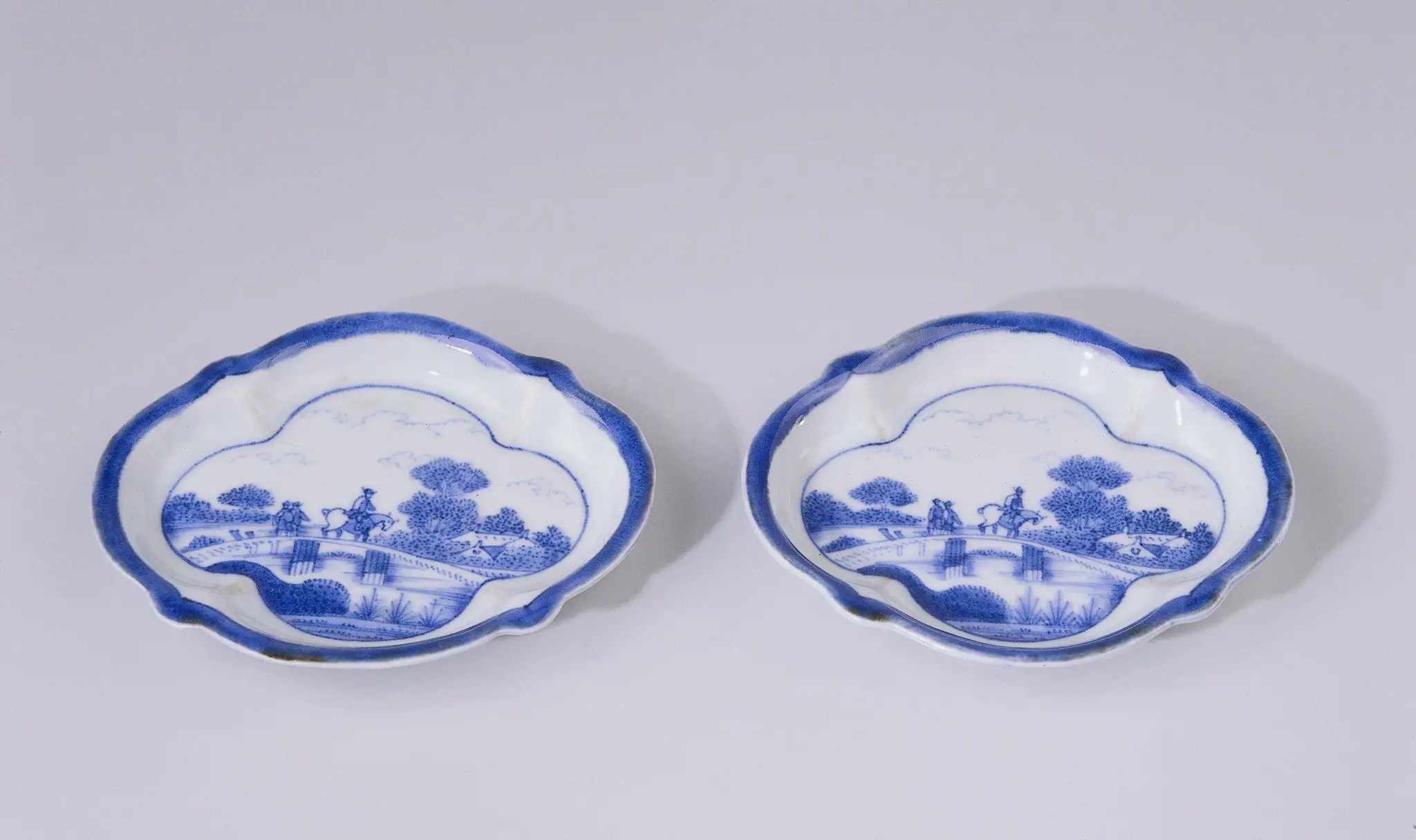 Saucer with figures on a bridge in a water landscape with trees and houses by anonymous