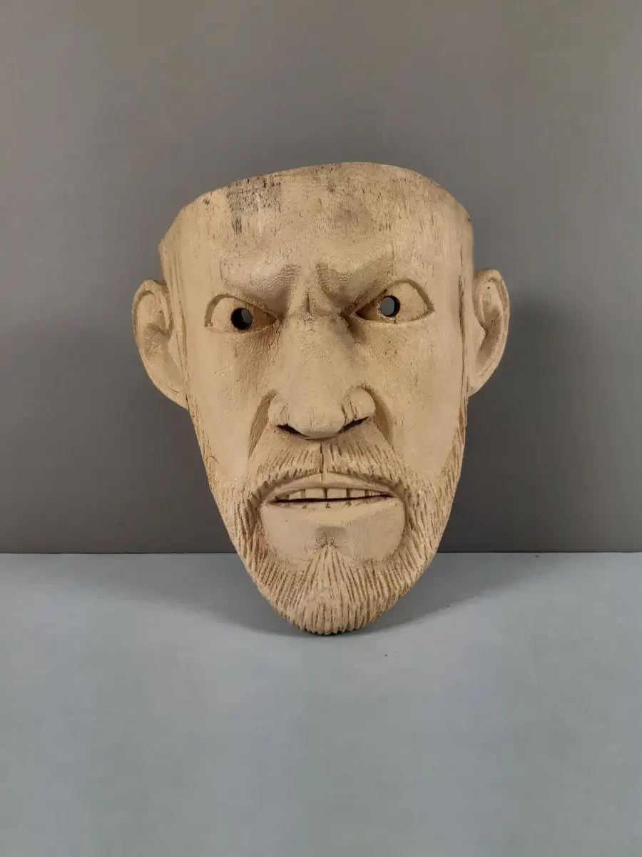 Snidad mask av ljust trä föreställande en arg man med skägg och mustasch by Okänd konsntär